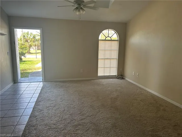 Spare room featuring ceiling fan, light carpet, and light tile patterned flooring