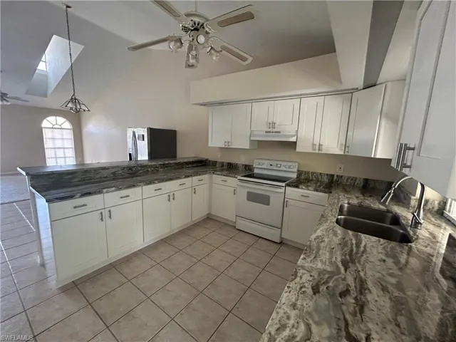 Kitchen featuring a ceiling fan, white range with electric cooktop, white cabinetry, dark stone countertops, and light tile patterned flooring