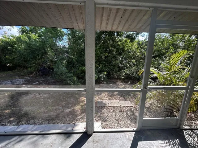 Unfurnished sunroom featuring plenty of natural light and view of wooded area