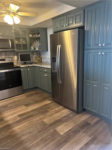 Kitchen featuring range, dark hardwood / wood-style floors, built in microwave, and stainless steel fridge