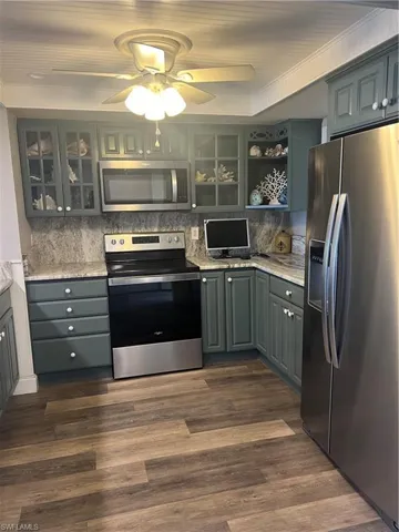 Kitchen with dark hardwood / wood-style floors, range, tasteful backsplash, and refrigerator