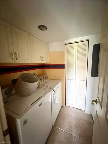 Laundry room featuring electric panel, cabinets, washer and dryer,