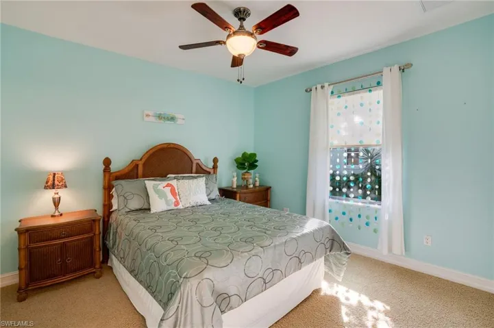 Bedroom with a ceiling fan and light colored carpet