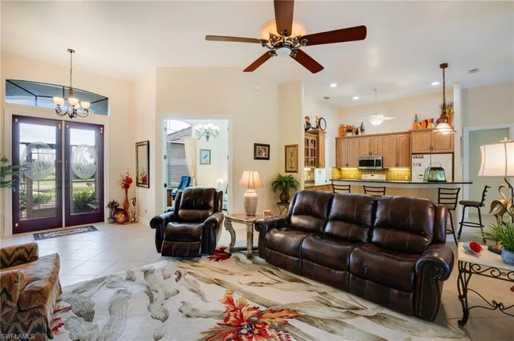 Living room with light tile patterned floors, ceiling fan, french doors, and a chandelier
