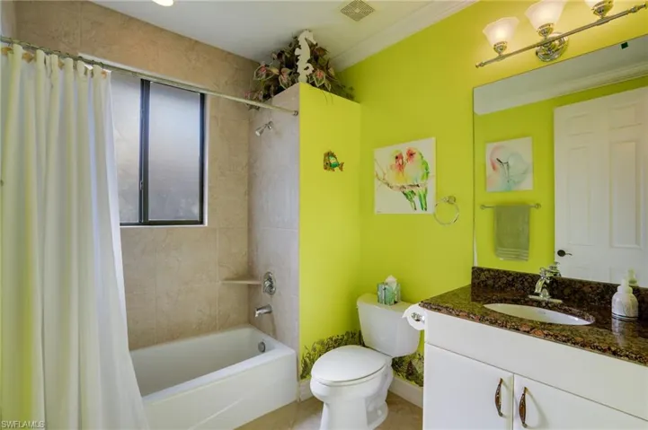 Full bath with vanity, shower / bath combination with curtain, ornamental molding, and light tile patterned floors