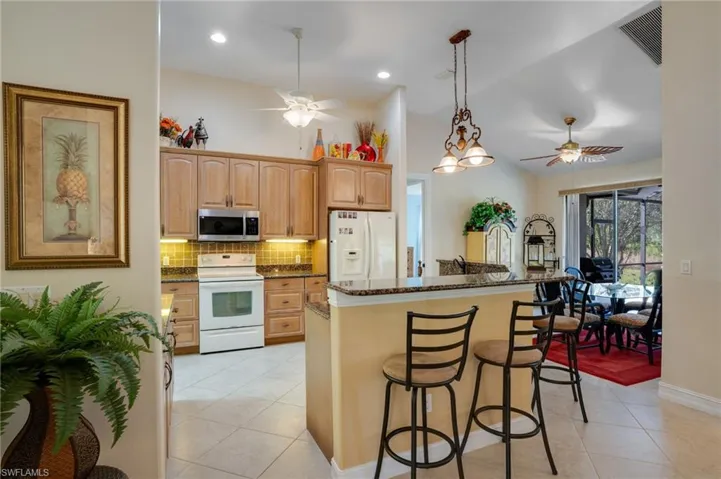 Kitchen with light tile patterned floors, pendant lighting, white appliances, a ceiling fan, and lofted ceiling