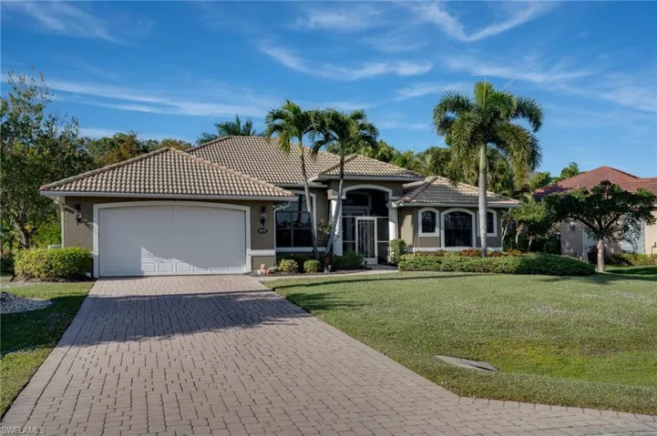 Mediterranean home featuring a tile roof, stucco siding, decorative driveway, and a front lawn
