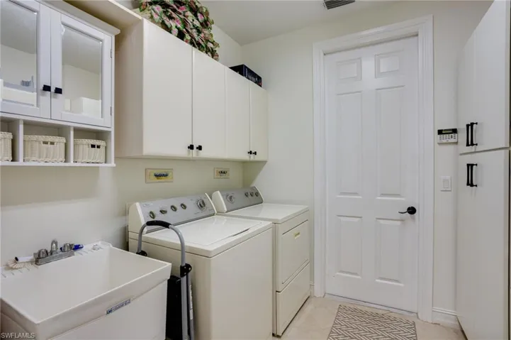 Washroom featuring cabinet space, washing machine and clothes dryer, and light tile patterned floors