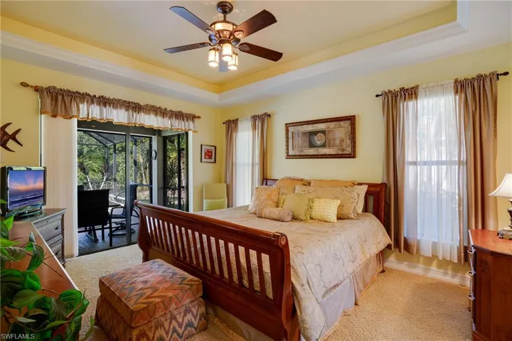 Bedroom with access to outside, a raised ceiling, multiple windows, and ceiling fan