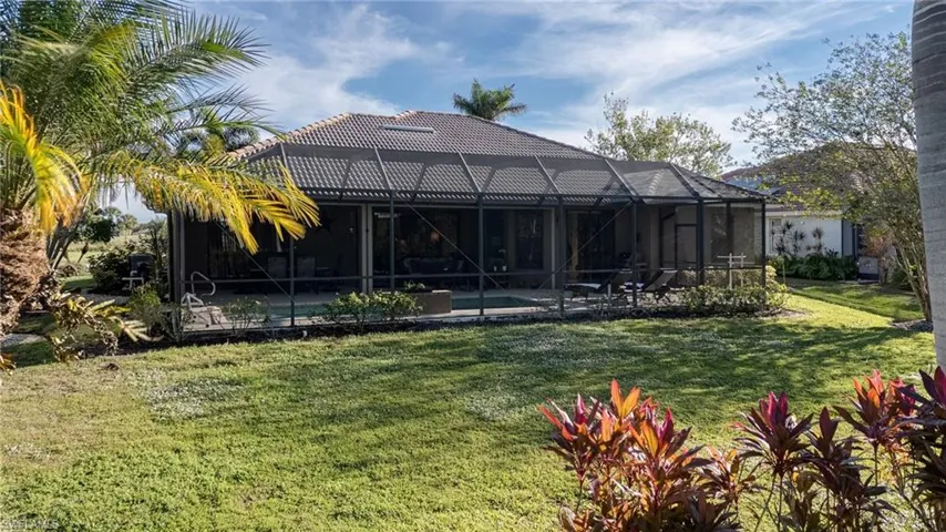 Rear view of property featuring an outdoor pool, glass enclosure, a sunroom, and a lawn