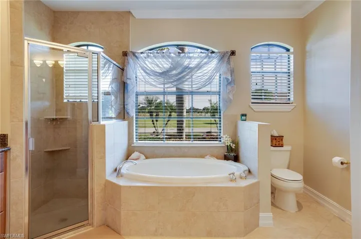 Bathroom with a garden tub, a shower stall, plenty of natural light, tile patterned flooring, and crown molding