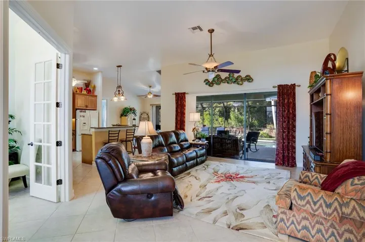 Living area with light tile patterned floors, lofted ceiling, and a ceiling fan