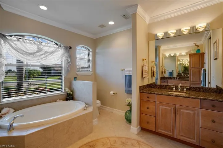 Bathroom featuring vanity, a garden tub, crown molding, recessed lighting, and light tile patterned floors