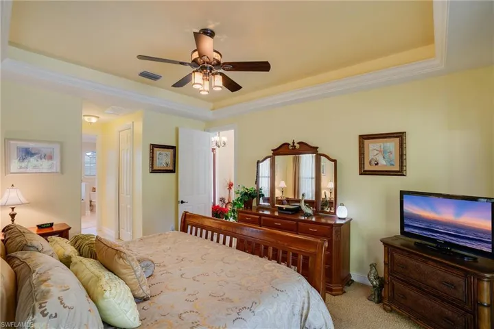 Bedroom with carpet flooring, a tray ceiling, a ceiling fan, and crown molding