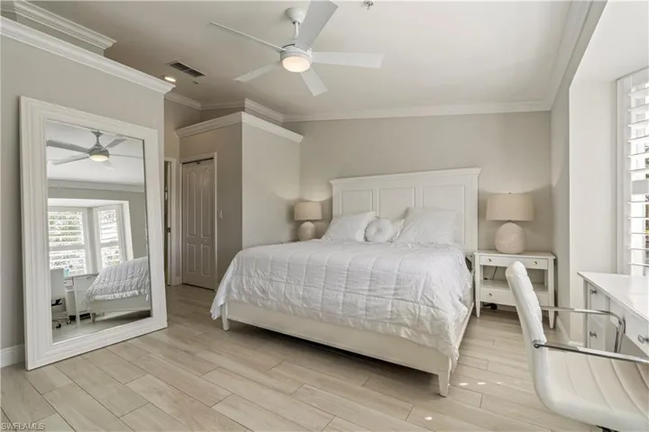 Bedroom with a ceiling fan, light wood-style flooring, baseboards, visible vents, and ornamental molding