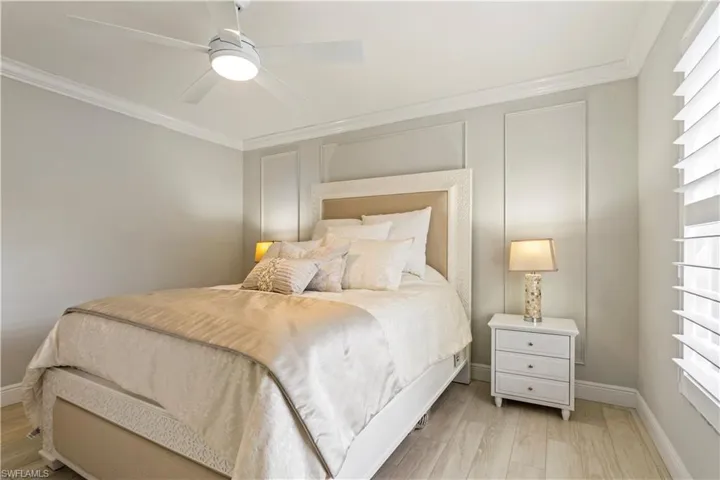 Bedroom with baseboards, light wood-style flooring, ornamental molding, and a ceiling fan