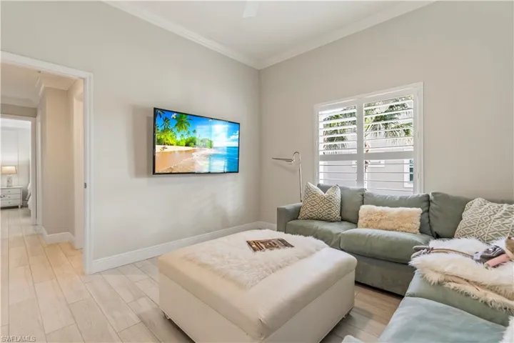 Living room with light wood-style flooring, crown molding, and baseboards
