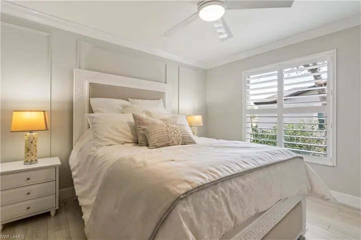 Bedroom featuring light wood finished floors, baseboards, crown molding, and ceiling fan
