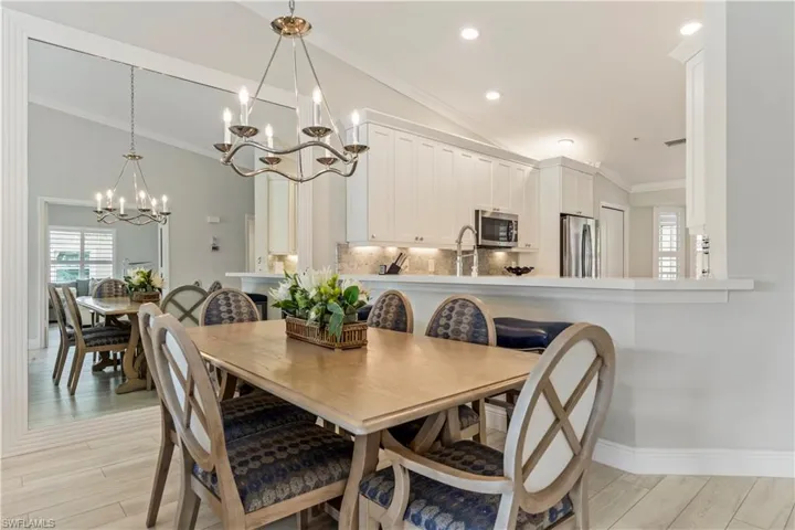 Dining space with crown molding, vaulted ceiling, recessed lighting, a chandelier, and light wood-style floors