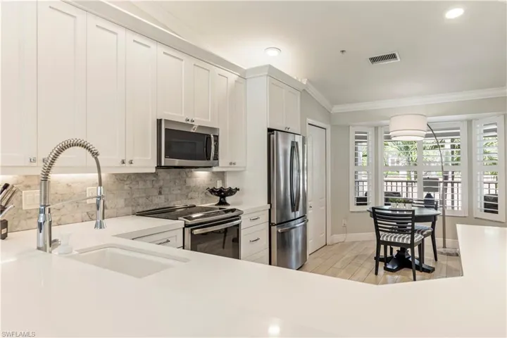 Kitchen with visible vents, crown molding, stainless steel appliances, tasteful backsplash, and a sink