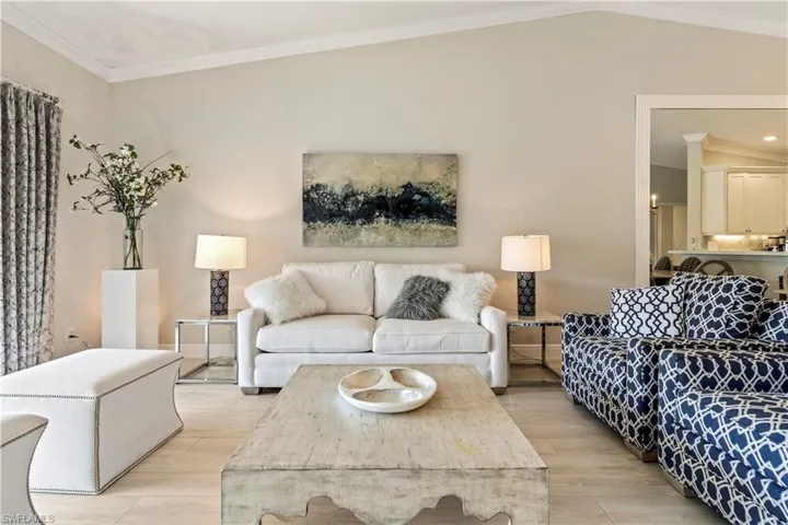 Living area featuring lofted ceiling, crown molding, and light wood-style floors