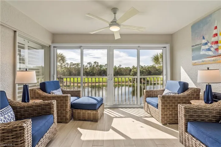 Sunroom / solarium with a water view, a textured wall, and a ceiling fan