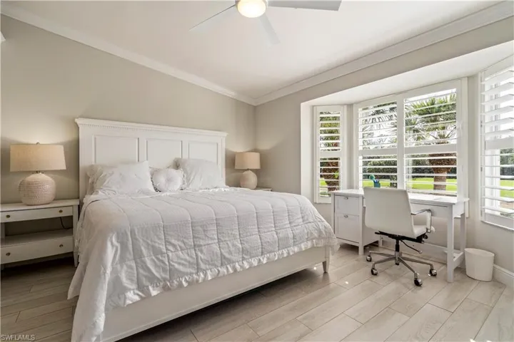 Bedroom with a ceiling fan, ornamental molding, baseboards, and light wood finished floors