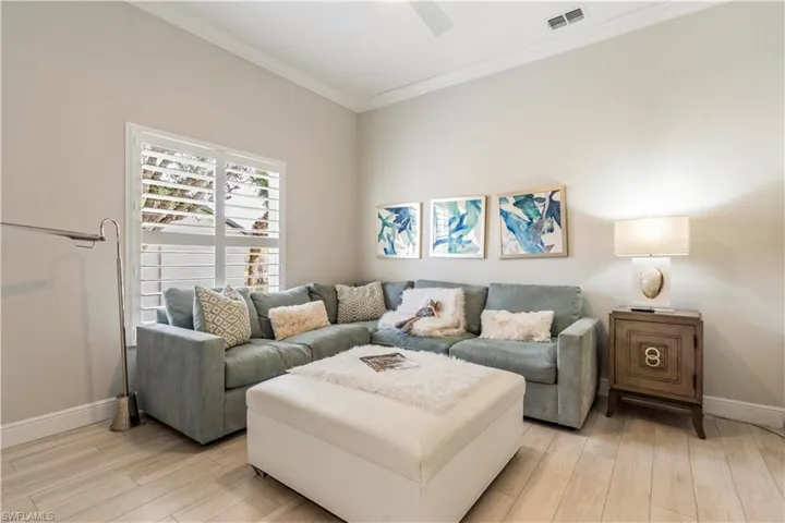 Living area featuring baseboards, visible vents, crown molding, and light wood-type flooring