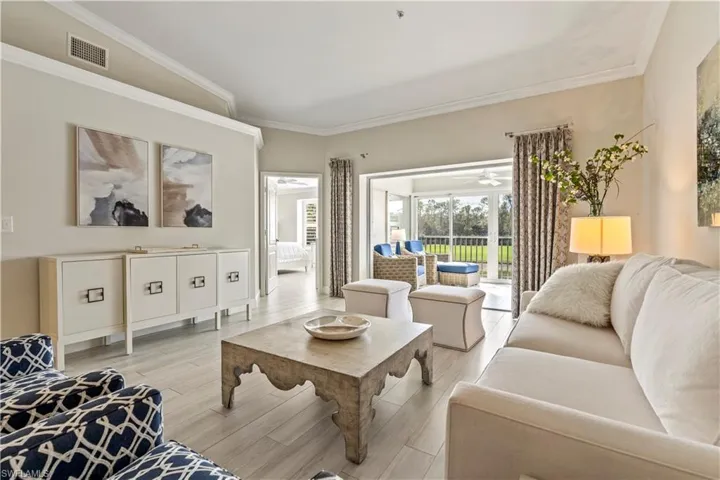 Living area featuring visible vents, crown molding, light wood-style flooring, and a ceiling fan