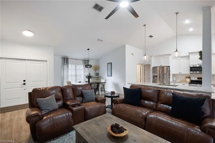 Living room with ceiling fan, lofted ceiling, sink, and light hardwood / wood-style flooring