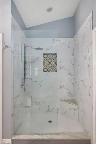 Bathroom with a tile shower and vaulted ceiling