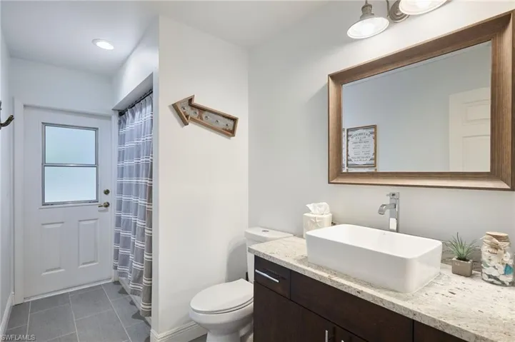 Bathroom featuring curtained shower, vanity, and toilet