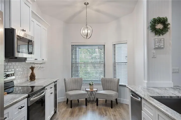 Kitchen featuring hanging light fixtures, white cabinetry, light hardwood / wood-style flooring, appliances with stainless steel finishes, and backsplash