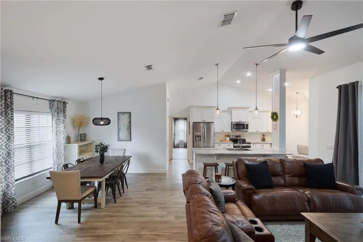 Living room with sink, vaulted ceiling, light hardwood / wood-style flooring, and ceiling fan