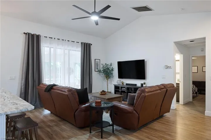 Living room featuring ceiling fan, hardwood / wood-style flooring, and high vaulted ceiling
