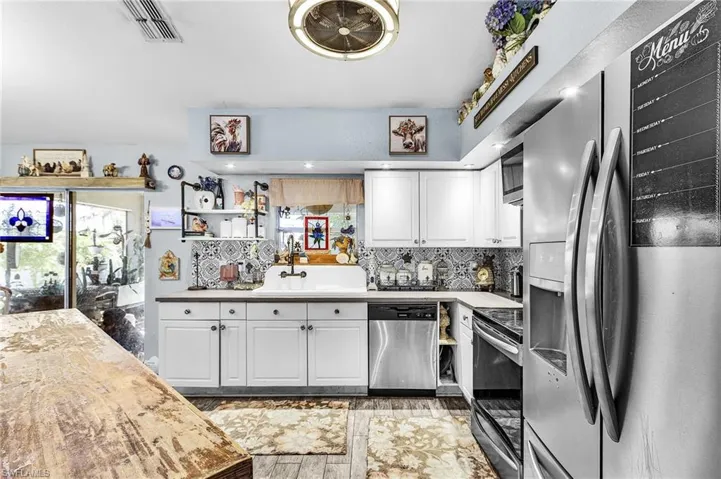 Kitchen featuring stainless steel appliances, white cabinetry, backsplash, open shelves, and light wood finished floors