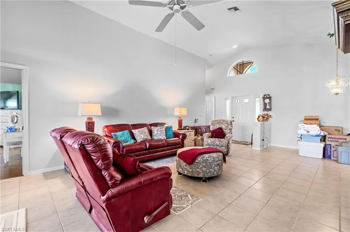 Living area featuring high vaulted ceiling, light tile patterned floors, and ceiling fan