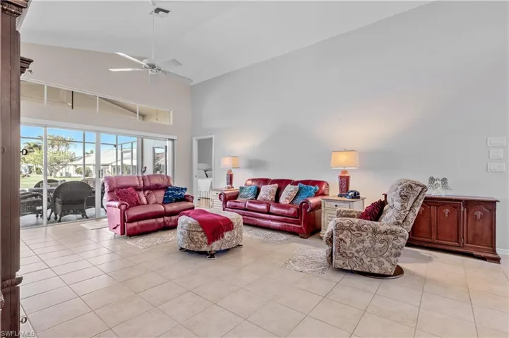 Living room featuring high vaulted ceiling, light tile patterned floors, and ceiling fan