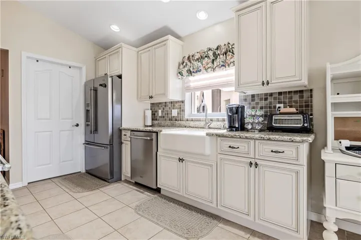 Kitchen with appliances with stainless steel finishes, light stone counters, tasteful backsplash, light tile patterned flooring, and recessed lighting
