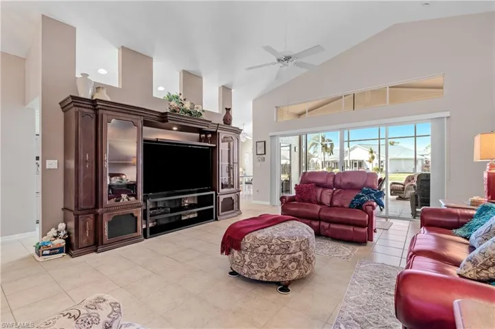 Living room featuring high vaulted ceiling, ceiling fan, and light tile patterned floors