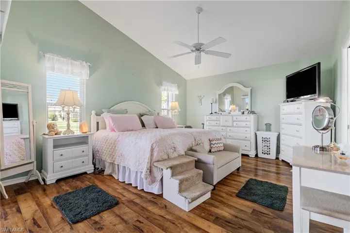 Bedroom featuring dark wood-type flooring, ceiling fan, and high vaulted ceiling