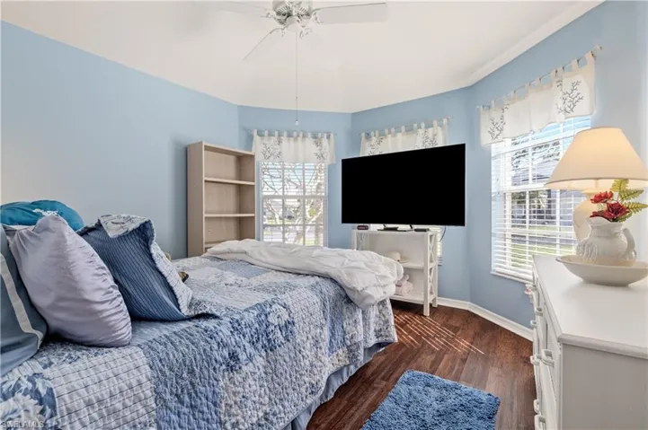 Bedroom with dark wood-type flooring, multiple windows, and ceiling fan