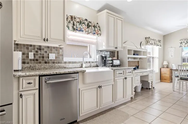 Kitchen featuring decorative backsplash, dishwasher, light tile patterned floors, light stone countertops, and ceiling fan