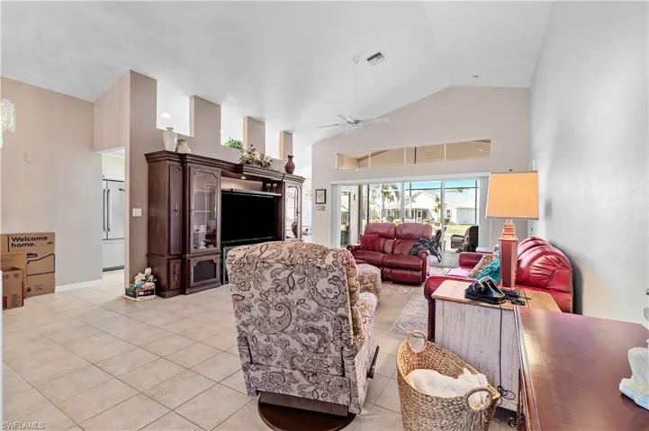 Living area featuring high vaulted ceiling, light tile patterned floors, and ceiling fan