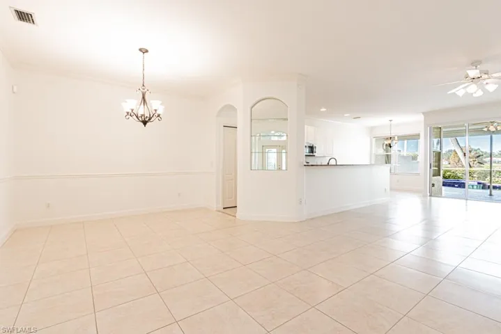 Unfurnished room featuring a chandelier, crown molding, light tile patterned floors, and a ceiling fan