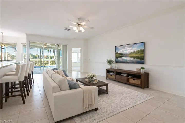 Virtually Staged Living room featuring light tile patterned flooring, ornamental molding, and a ceiling fan