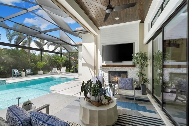 Swimming pool featuring an outdoor living space with a fireplace, a patio area, a lanai, and a sunroom