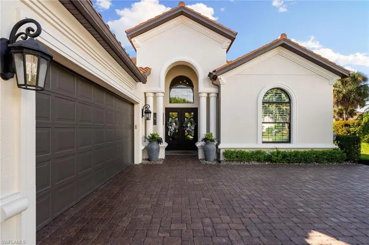 Property entrance with french doors, decorative driveway, stucco siding, and an attached garage