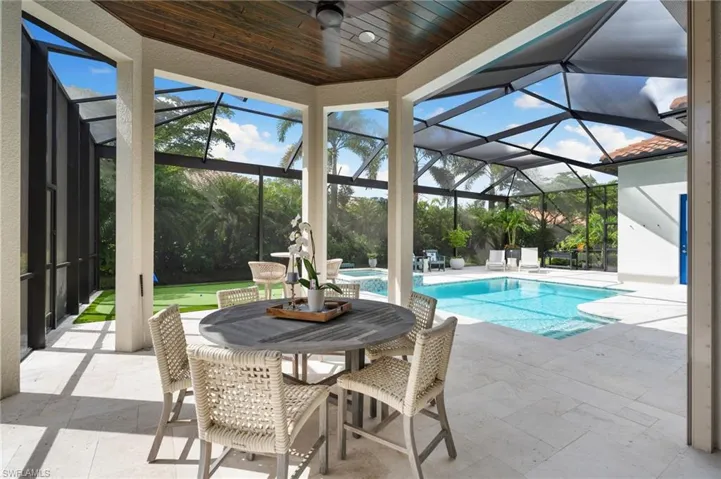 Swimming pool featuring a patio, glass enclosure, a sunroom, outdoor dining space, and ceiling fan