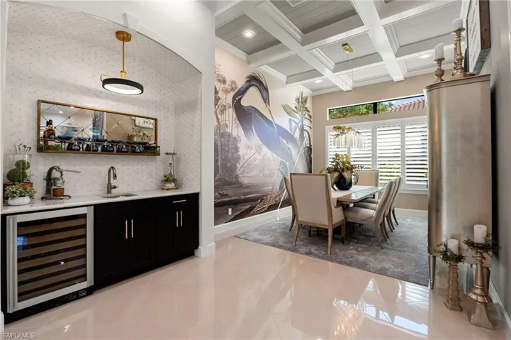 Dining room featuring wine cooler, beamed ceiling, coffered ceiling, wet bar, and crown molding